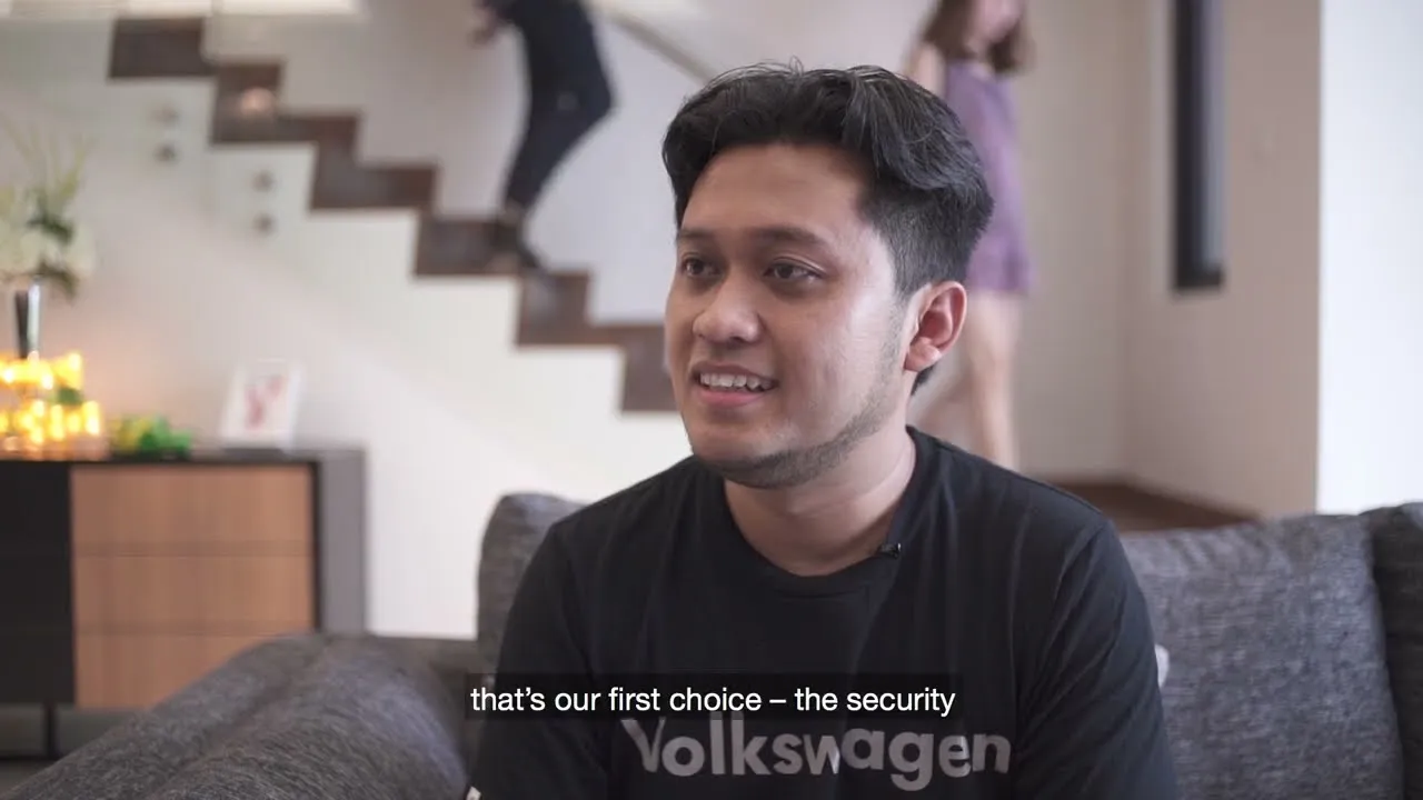 A OnePark homeowner seated on the sofa in his living room, the home’s open staircase behind him